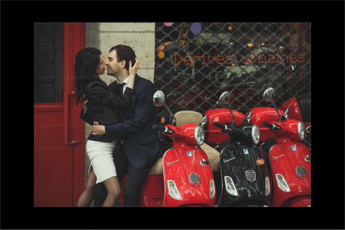 Engaged couple leaning in for a kiss while sitting on scooters in Paris