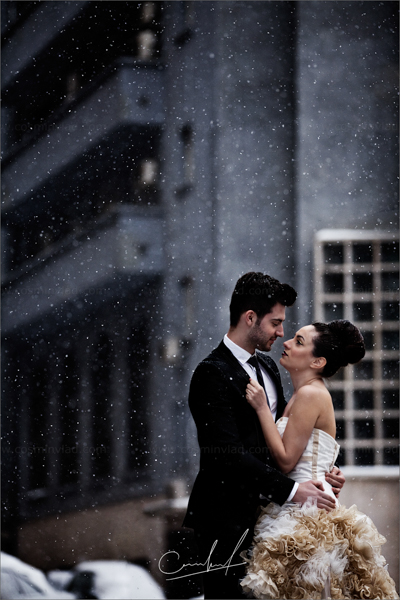 Bride and groom holding each other under snowflakes
