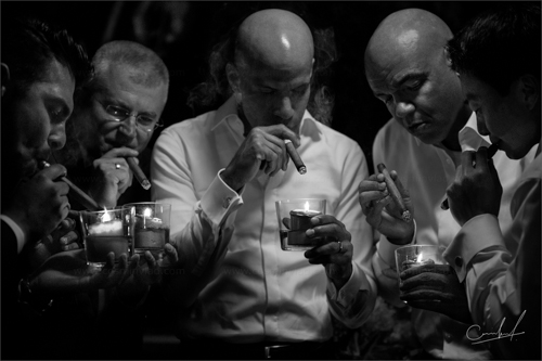 Groom smoking cigar with male guests